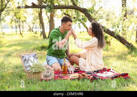 Der Freund küsst die Hand seiner Freundin auf einem romantischen Picknick im Park Stockfoto