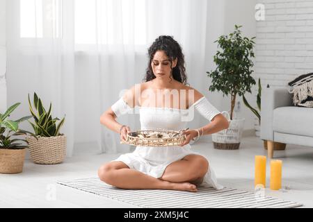 Wunderschöne afroamerikanische Schamanin, die zu Hause ein Ritual durchführt Stockfoto