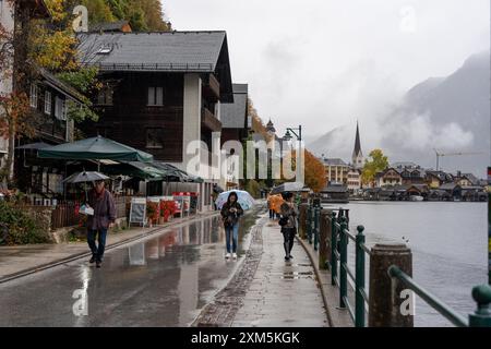 Hallstatt, Österreich - 31. Oktober 2023 : regnerischer Tag in Hallstatt, Österreich, an dem Menschen auf einer nassen Kopfsteinpflasterstraße am See spazieren gehen. Stockfoto