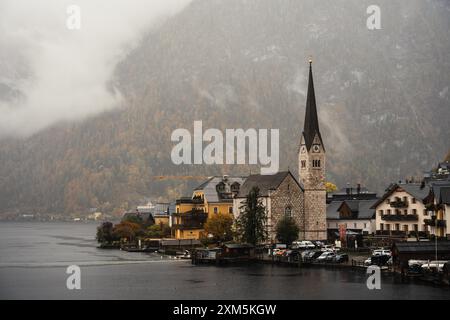 Hallstatt, Österreich - 31. Oktober 2023 : Ein Kirchturm durchsticht die Wolken über Hallstatt, Österreich, eine malerische Seestadt mit einer Kulisse von mi Stockfoto