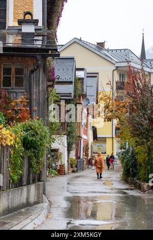 Hallstatt, Österreich - 31. Oktober 2023 : Eine schmale Straße in Hallstatt, Österreich, mit bunten Gebäuden und einer nassen, kopfsteingepflasterten Straße. Stockfoto