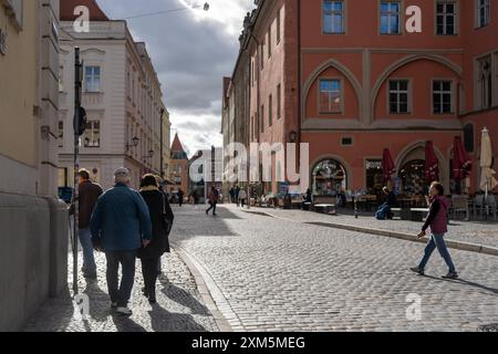 Regensburg, Deutschland - 06. November 2023 : Kopfsteinpflasterstraße in Regensburg, wo Menschen an Geschäften und Cafés vorbeilaufen. Stockfoto