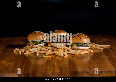 Drei Hamburger und eine Seite Pommes Frites auf einem Holztisch Stockfoto