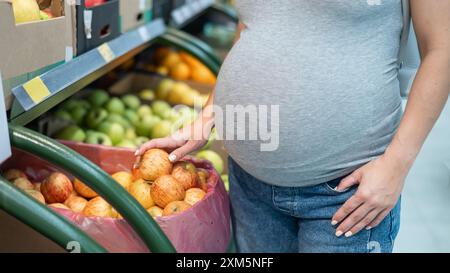 Schwangere Frau wählt Äpfel im Laden. Stockfoto