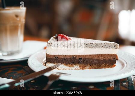 Alanya, Türkei, 17. September 2020: Erdbeer-Schokoladenkuchen mit Cappuccino auf einem Holztisch in einem Café Stockfoto