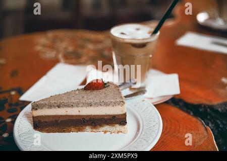 Alanya, Türkei, 17. September 2020: Erdbeer-Schokoladenkuchen mit Cappuccino auf einem Holztisch in einem Café Stockfoto