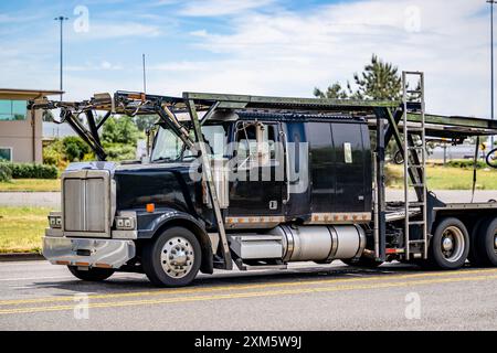 Industrieträger schwarzer Kfz-Transportwagen großer Lkw-Sattelzugmaschine mit verlängerter Kabine für LKW-Fahrer, die leeren Auflieger transportieren, die auf dem fahren Stockfoto