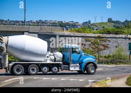 Industrieträger Blue Day Cab Sattelzugmaschine mit großem Lkw, die Beton im Mischanhänger zur Bauseite transportiert, die mit rund auf der Straße läuft Stockfoto