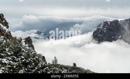 Ätherische Schönheit in den Dolomiten: Schneebedeckte Berge umgeben von weißen Wolken im Juni Stockfoto