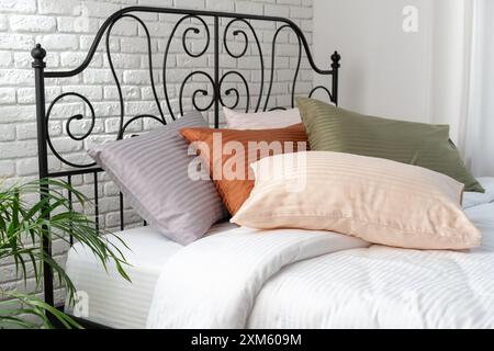Gestreifte Kissen auf einem Bett mit Kopfteil aus schwarzem Metall Stockfoto