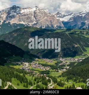 Vom Wanderweg Sella Group aus bewundern Sie das bezaubernde Dorf Colfosco vor einer dramatischen Bergkulisse, das die atemberaubende Bergkulisse zeigt Stockfoto