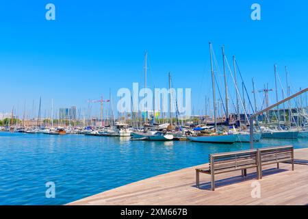 Barcelona, Spanien - 16. Juli 2024: Charmante Holzbank an der Küste von Barcelona mit malerischem Blick auf Segelboote im mar Stockfoto