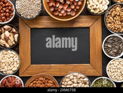 Erdnuss, Haselnuss, Walnuss, Mandeln, Pistazien, Sonnenblumen, Kürbis, Chia, Pekan und Cashew gemischt gesunde Nüsse und Samen mit Menübrett. Stockfoto