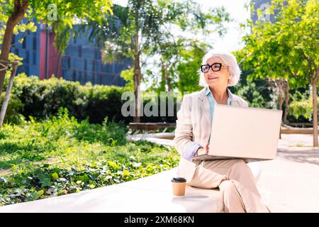 Frau mittleren Alters, die im Freien einen Laptop benutzt Stockfoto