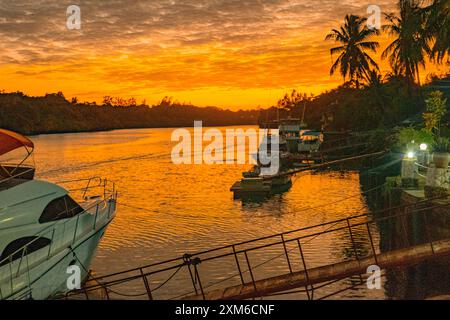 Silhouette von Booten gegen Palmen bei Sonnenuntergang in Mtwapa Creek, Mtwapa Town in Kenia Stockfoto