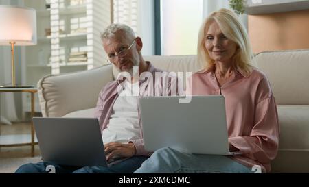 Ältere kaukasische Großeltern ältere verheiratete ältere Ehepaare Familienfrau weiblicher Mann männlicher Lächeln Arbeit online Tippen Laptops pc Geschäftsfrau Ehemann Stockfoto