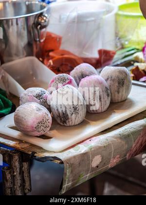 Ein Mann, der ein blaues Hemd trägt, schneidet große Stücke gebratener Schweinehaut Stockfoto