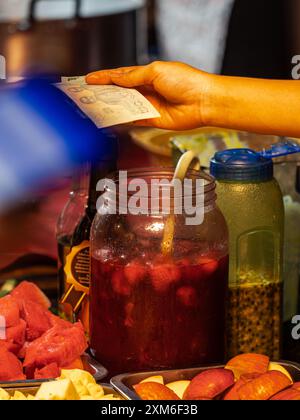 Frisches Obst und Getränke an einem Marktstand bezahlen Stockfoto