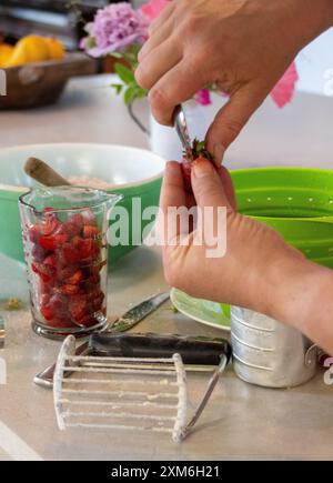 Hände, die Erdbeeren für die Herstellung von Scones in der Küche vorbereiten Stockfoto