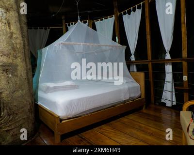 Nauta, Peru - April 2022: Riesiges Bett mit weißem Moskitonetz. Glamping-Unterkunft im Amazonas-Regenwald. Baumhaus aus Holz, Amazonas Regenwald, Amaz Stockfoto