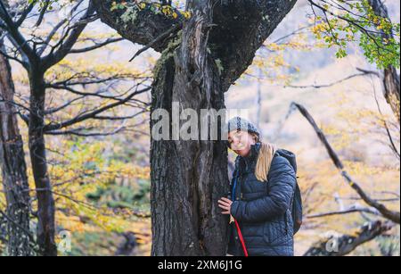 Eine Frau umarmt einen Baumstamm in einem Wald Stockfoto