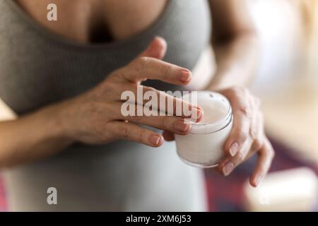 Seniorin in den 60er Jahren, die Handcreme auf die Haut der Hände pflegt Stockfoto