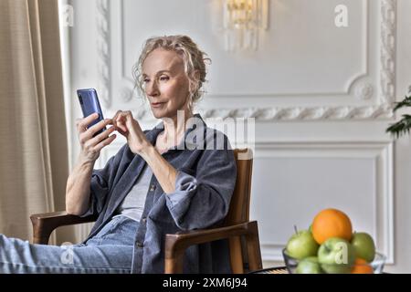 Lächelnde Seniorin nutzt App auf dem Handy Stockfoto