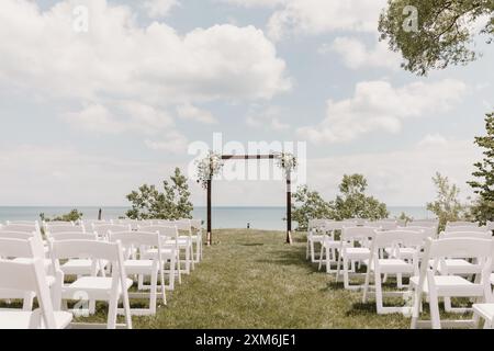 Hochzeitszeremonie am See im Freien mit weißen Stühlen und Blumen Stockfoto