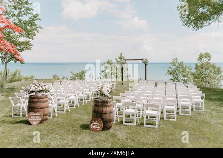 Hochzeitszeremonie am See im Freien mit weißen Stühlen und Blumen Stockfoto