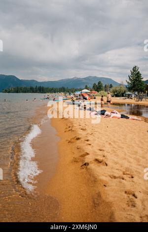 Menschen am Strand eines Sees, die sich sonnen und paddeln Stockfoto