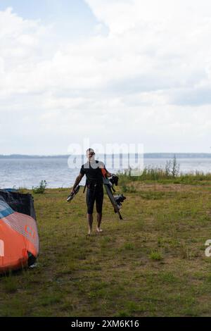 Ein Kitesurfer kommt nach dem Reiten mit seinem Drachen aus dem Wasser. Stockfoto