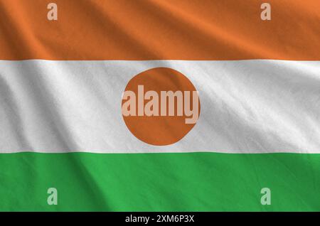 Niger-Flagge auf gefaltetem, gewelltem Stoff aus altem Tuch in Nahaufnahme dargestellt Stockfoto