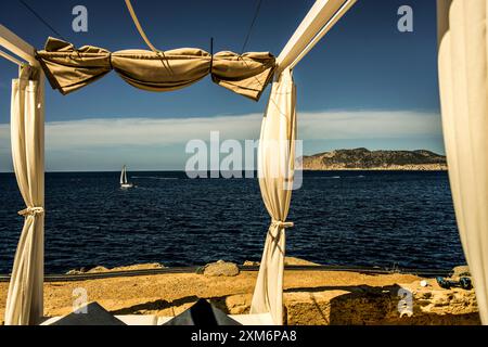 Blick vom balinesischen Bett auf der Terrasse des Hotels Sentido Fido Punta del Mar an der Costa de la Calma zu einem Segelboot in der Bucht in der Nähe von Santa Pon Stockfoto