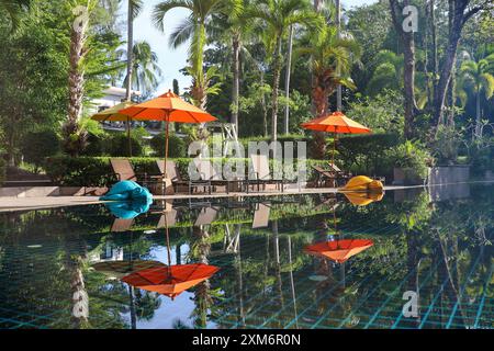 Tropischer Urlaub, Swimmingpool mit Sonnenschirmen und Liegestühlen umgeben von Palmen. Urlaub im Paradies Garten, Strandresort Stockfoto