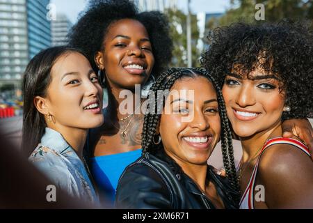 Verschiedene Gruppen fröhlicher Freundinnen, die an einem sonnigen Nachmittag in der Stadt ein Selfie machen Stockfoto