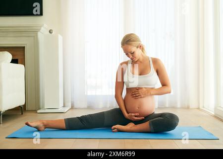 Yoga, Entspannung und schwangere Frau berühren den Bauch zu Hause für Sport, Wellness oder pränatale Pflege. Pilates, Schwangerschaft und zukünftige Mutter mit Magen Stockfoto