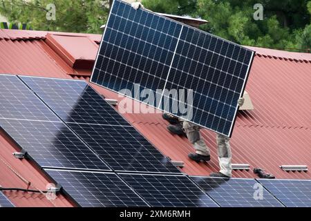 Arbeiter, die Solarpaneele auf dem Dach installieren, erneuerbare alternative Energiequellen Stockfoto