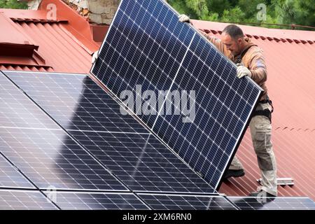 Arbeiter, der Solarpaneele auf dem Dachhaus installiert Stockfoto