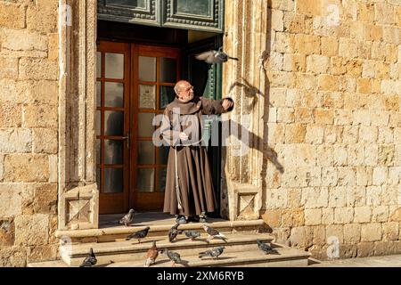 Mönch füttert die Tauben vor dem Franziskanerkloster Dubrovnik, Kroatien, Europa Stockfoto