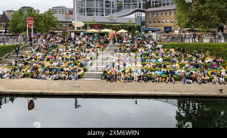 London, Großbritannien. Juli 2024. Die Leute sehen sich ein kostenloses Freiluftkino im Everyman on the Canal an, eine Großbildinstallation in Granary Square Steps, King's Cross, trotz des feuchten und wechselhaften Wetters heute, und scheinen ihren Sommer in der Stadtunterhaltung zu genießen. Everyman on the Canal zeigt täglich 4 Filme zwischen dem 1. Juli und dem 18. August. Quelle: Imageplotter/Alamy Live News Stockfoto