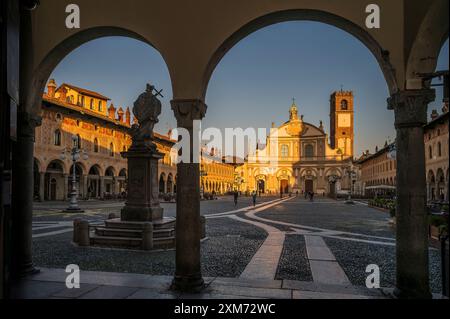 Blick durch Arkaden zur Piazza Ducale mit der Kathedrale von Vigevanono Cattedrale di Sant'Ambrogio am Ende des Platzes, Vigevano, Provinz Pav Stockfoto