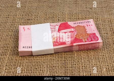 Stapel von 100 pakistanischen Rupien-Banknoten auf Sackleinen-Oberfläche Stockfoto