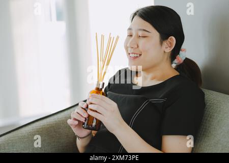 Frau glücklich mit Öl Aroma Sticks Heim Luft Auffrischung Duft Diffusor guter Geruch Raum Parfüm Relax Lächeln Stockfoto