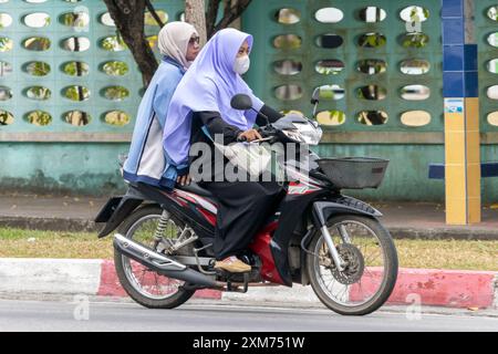 YALA, THAILAND, 1. März 2024, Eine Frau in traditioneller Kleidung fährt mit einem Motorrad Stockfoto