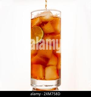 Cola auf Eis in einem hohen Glas mit Limettenscheibe auffüllen Stockfoto