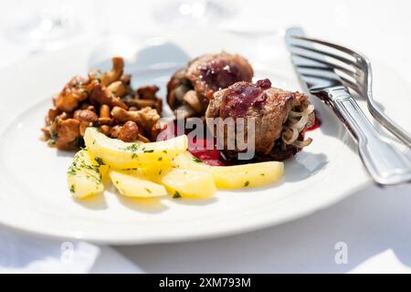 Wildschweinroulade mit Preiselbeerjus, Pfifferlingen und Kartoffeln Stockfoto