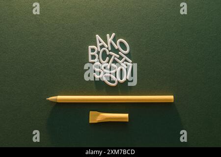 Weiße Plastikbuchstaben und ein gelber Stift auf grüner Textur. Back-To-School-Konzept Stockfoto