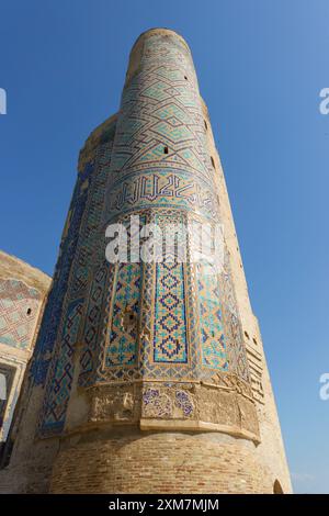 Antike türkisfarbene Mosaikturm mit islamischer Kalligraphie und komplizierten Keramikfliesen unter einem klaren blauen Himmel in Samarkand, Usbekistan Stockfoto