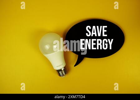 Energiespartext auf Sprechblase mit Glühlampe Draufsicht auf gelbem Hintergrund speichern Stockfoto