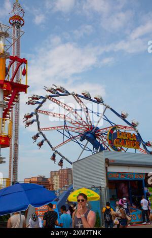 Leute auf den Fahrgeschäften im Vergnügungspark an der Promenade auf Coney Island, Brooklyn, New York. Stockfoto